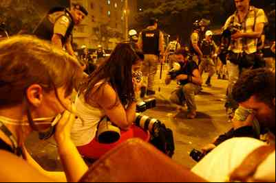 Mariela, no centro da imagem, se protege do gás lacrimogêneo ao lado de colegas jornalistas e fotógrafos